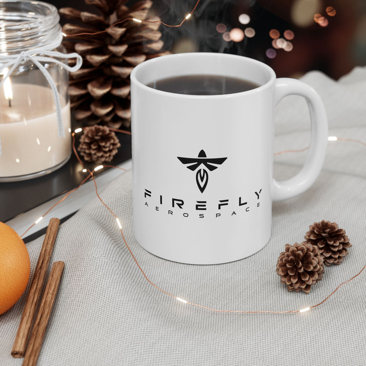 White mug with a cartoon design featuring a fairy and text, surrounded by decorative items on a table.