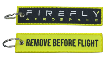 Two keychains with 'Firefly Aerospace' and 'Remove Before Flight' text on a white background.