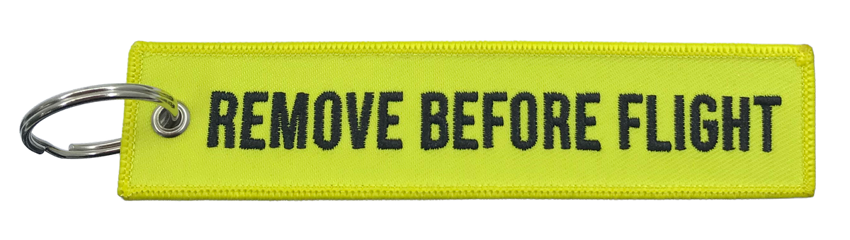 Yellow keychain with 'REMOVE BEFORE FLIGHT' text on a white background
